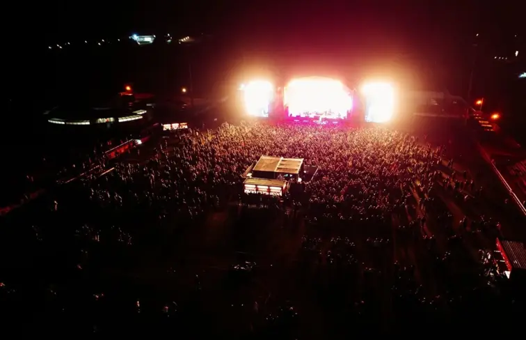 Uma imagem aérea de um espetáculo no festival, com muitas pessoas.